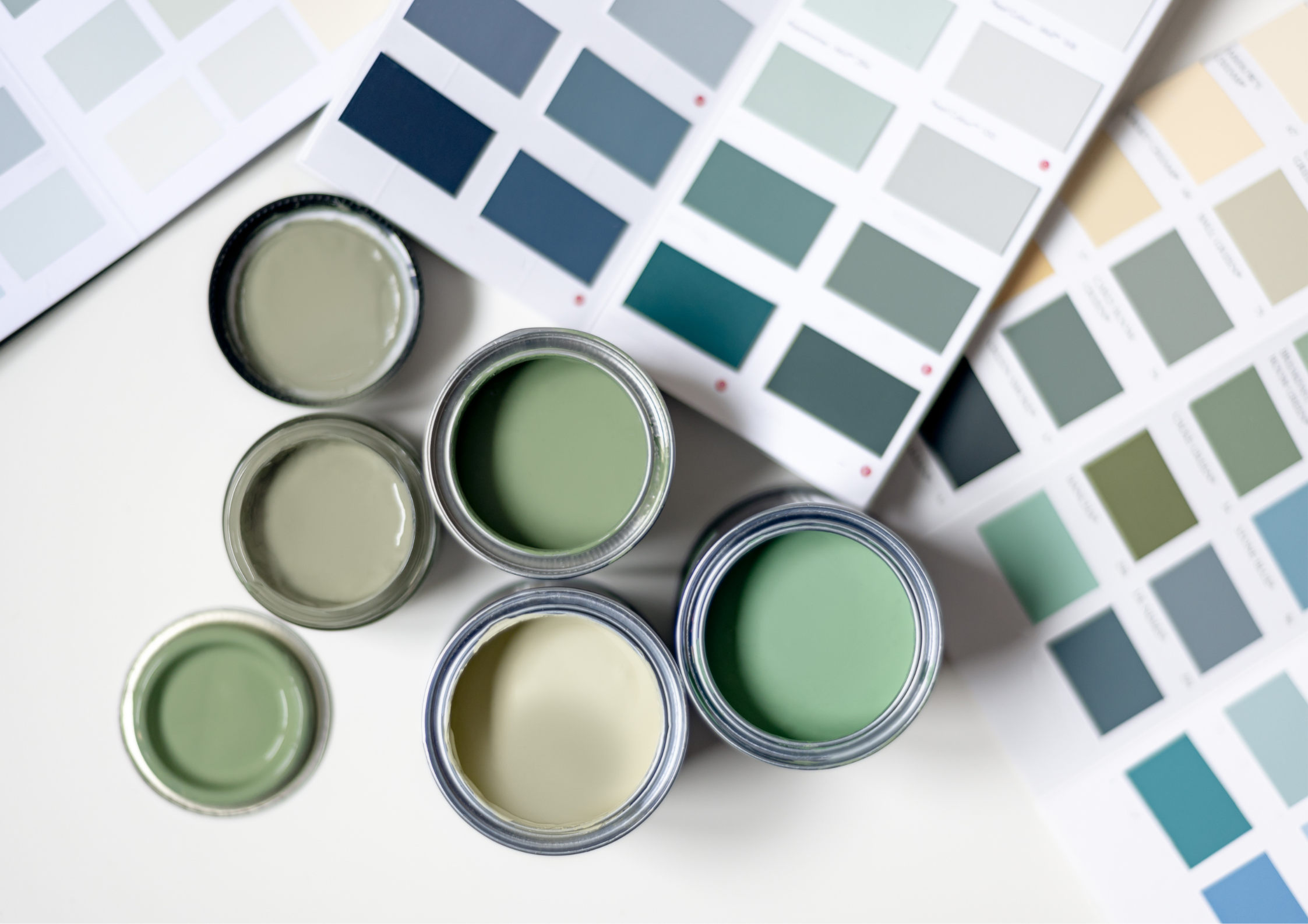Plusieurs pots de peinture aux teintes vertes vus de haut.